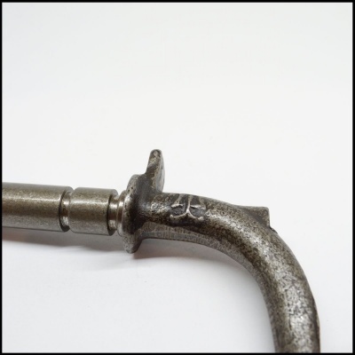 Parte metálica envelhecida de ferramenta com peça curva e marcas