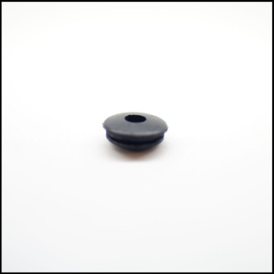 Peça pequena redonda preta com orifício central sobre superfície branca