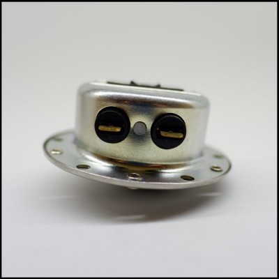 Peça metálica com terminais eléctricos pretos sobre fundo branco