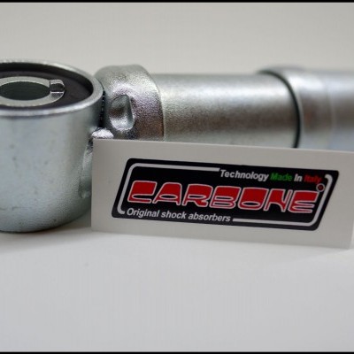 Amortecedor metálico prateado com autocolante 'CARBONE Original shock absorbers' em fundo branco