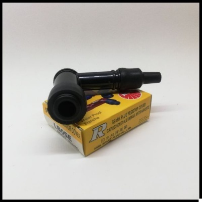 Tampa de vela de ignição preta com cabo sobre caixa amarela com texto em inglês.