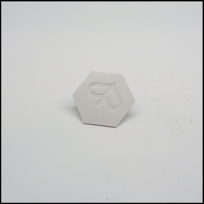 Objeto hexagonal branco com relevo em forma de R