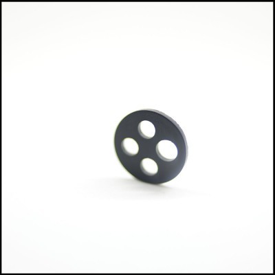 Disco redondo preto com quatro furos sobre fundo branco