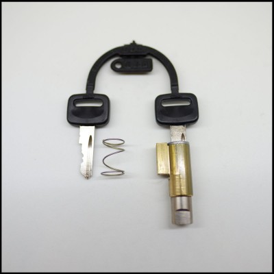 Chave e cilindro de fechadura com mola metálica sobre fundo branco