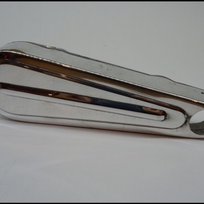 Peça metálica cromada com formato alongado e recorte circular