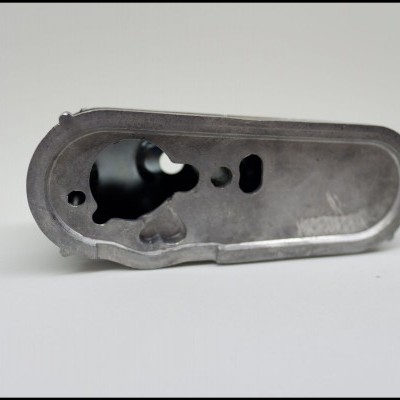 Peça metálica cinzenta com recortes sobre fundo branco