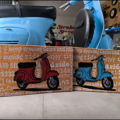 Dois tapetes com desenhos de scooters vermelha e azul numa oficina com scooter azul clara ao fundo