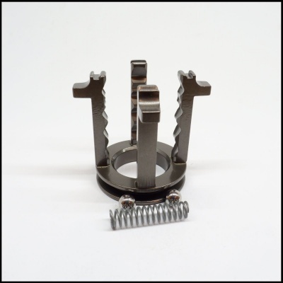 Peça metálica cinzenta com mola helicoidal e apoios verticais em fundo branco