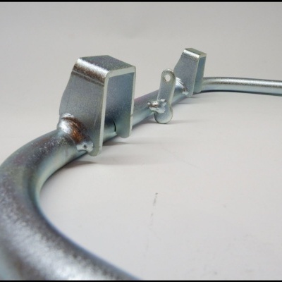 Peça metálica curva com fixadores e superfície brilhante sobre superfície branca