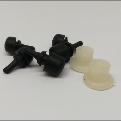 Cinco pequenos rolamentos de plástico, três pretos e dois transparentes, sobre fundo branco