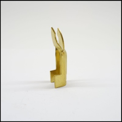 Terminal metálico dourado com duas pontas finas numa superfície branca