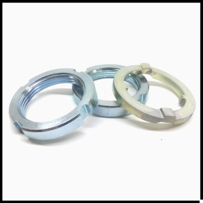 Três porcas de metal prateadas e amareladas com rosca interna sobre fundo branco