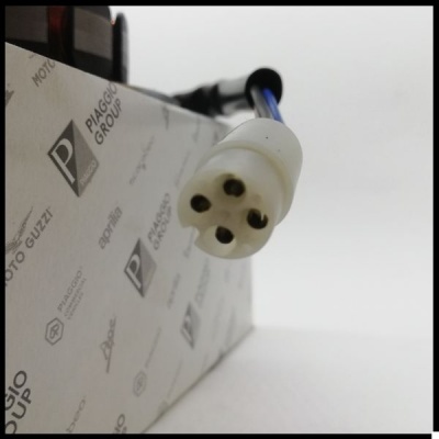 Conector elétrico branco com quatro pinos numa caixa com texto Piaggio Group