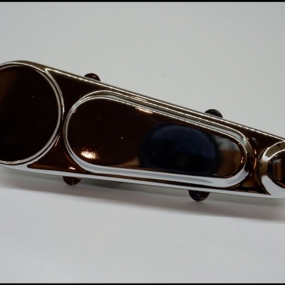 peça metálica cromada com círculos e seção oval sobre superfície branca