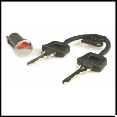 Cilindro de fechadura e duas chaves com cabos pretos ligadas por correia sobre fundo branco