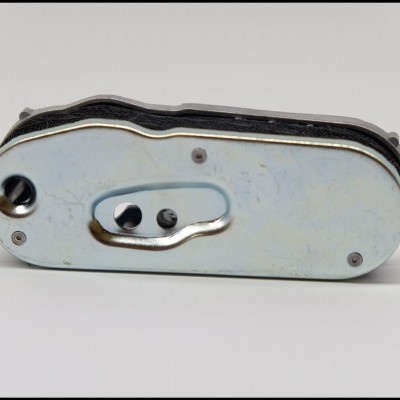 Aparelho metálico prateado com orifícios e parafusos sobre superfície branca