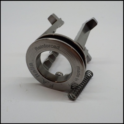 Componentes metálicos incluindo anel reforçado com texto e mola sobre fundo branco