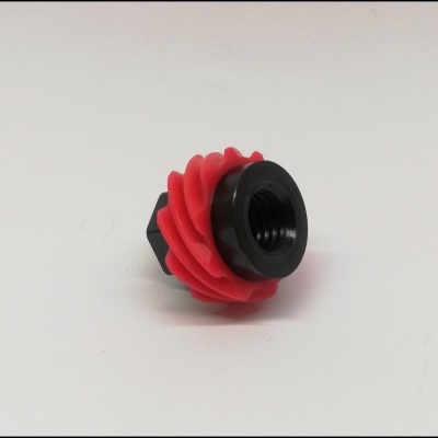 Peça plástica preta e vermelha com rosca interna numa superfície branca