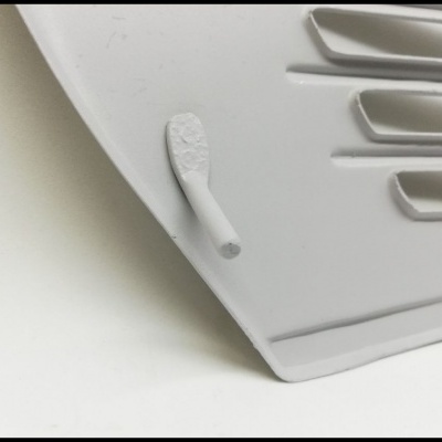 peça plástica branca com sulcos e aba protrusiva