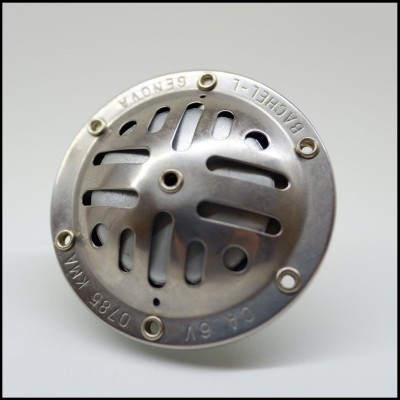 Dispositivo redondo metálico com parafusos e inscrições na borda em superfície branca