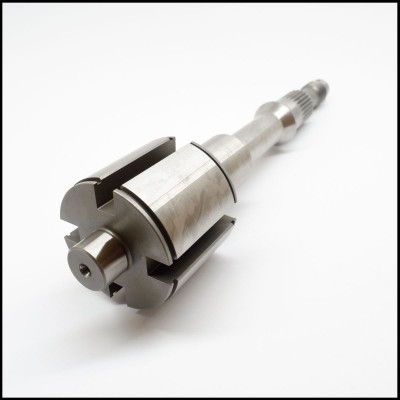 Peça metálica cilíndrica com ranhuras e furação sobre fundo branco.