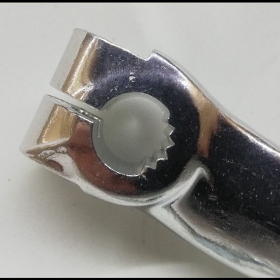 Peça metálica cromada com fenda circular dentada