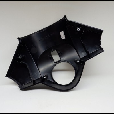 Peça plástica preta irregular com orifícios e etiqueta, sobre fundo branco