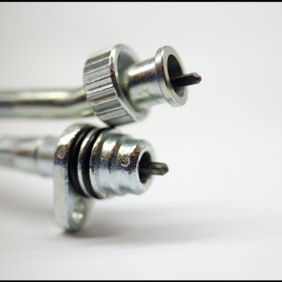 Duas válvulas metálicas cilíndricas com parafusos centrais e anéis de vedação em fundo branco