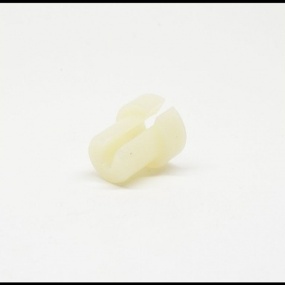 Peça pequena de plástico creme com formato curvado e fenda central
