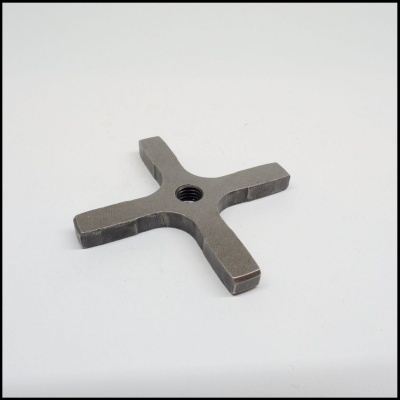 Peça metálica cruz com rosca central sobre superfície branca