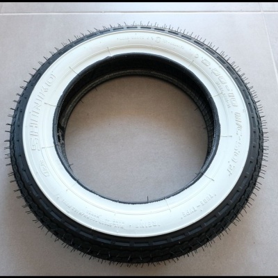 Pneu preto com faixa branca central sobre superfície clara