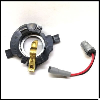 Peça eletrónica circular preta com componente metálico dourado e cabo com fios vermelho e preto