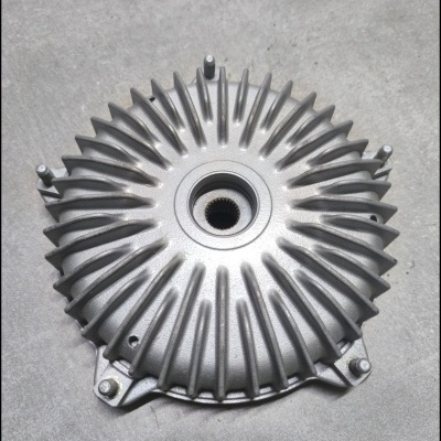 Peça metálica circular com aletas radiais cinzentas prateadas sobre superfície cinzenta