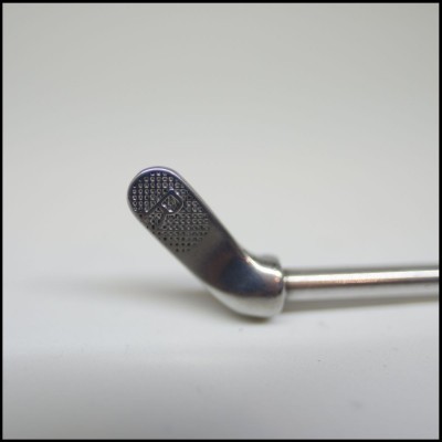 Utensílio metálico pontiagudo com letra P gravada em fundo branco