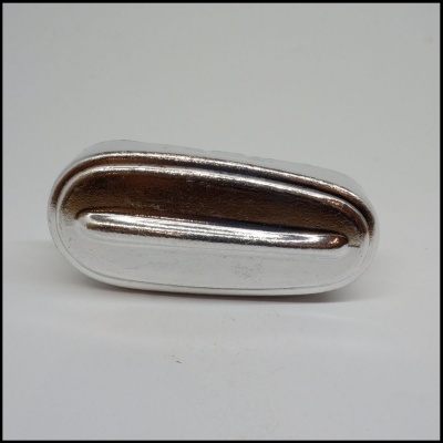 Objeto metálico oval prateado com relevo