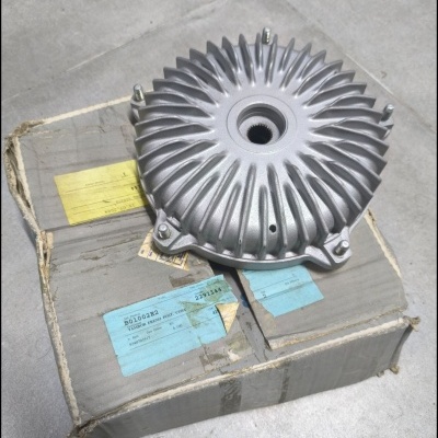 Peça metálica redonda com aletas radiais sobre caixa de cartão com etiquetas coloridas.