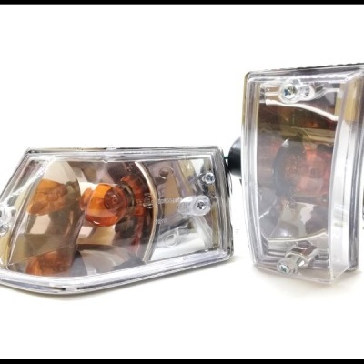 Dois faróis de automóvel com plástico transparente e detalhes em âmbar e prata