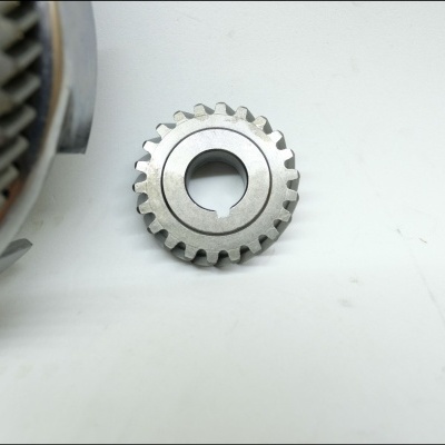 Engrenagem metálica prateada sobre superfície branca junto a peça mecânica