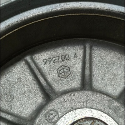 Peça metálica circular com número 992700 4 e textura rugosa