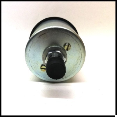 Rolo metálico cilíndrico com botão preto numa superfície branca