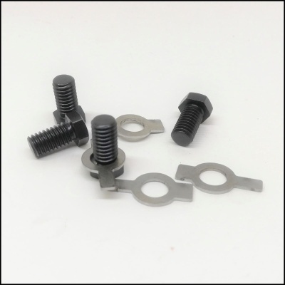 Parafusos pretos com arruelas metálicas prateadas sobre superfície branca