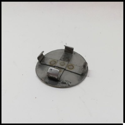 Peça metálica redonda com presilhas em fundo branco