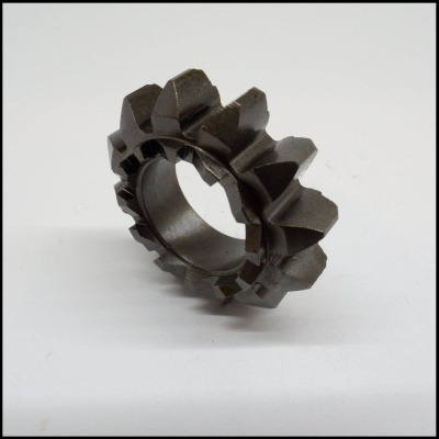 Engrenagem metálica cinza escuro com dentes largos sobre superfície branca