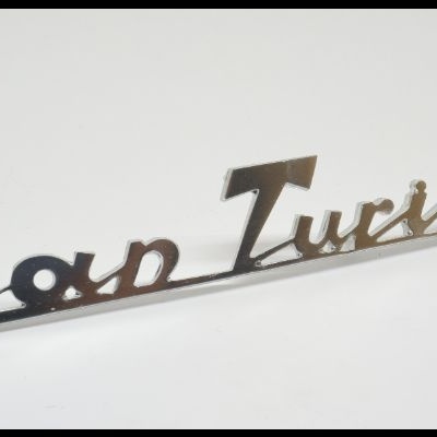 Insígnia metálica prateada com o texto Gran Turismo