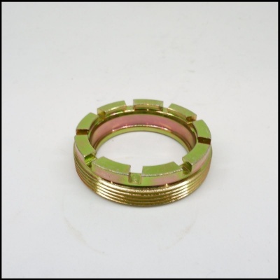 Anel metálico dourado com rosca e ranhuras sobre superfície branca