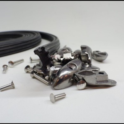 Parafusos metálicos com peças pequenas e correia preta sobre superfície branca