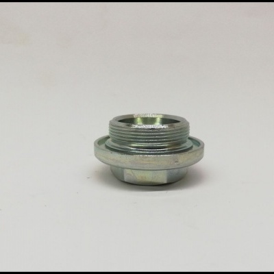 Peça metálica cilíndrica prateada com roscas, sobre superfície branca.