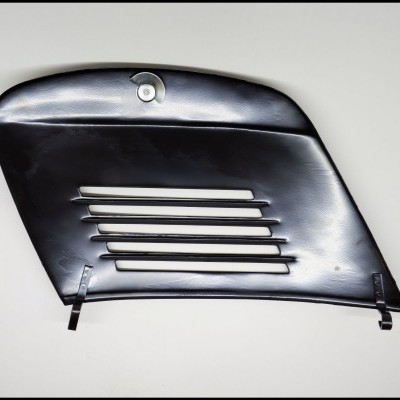 Peça lateral preta de motocicleta com ranhuras e fecho circular