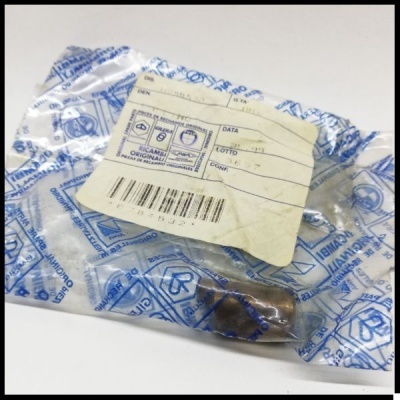 Peça metálica em embalagem plástica com etiqueta e texto em italiano