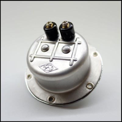 Produto metálico redondo com dois terminais pretos e base com furos para fixação